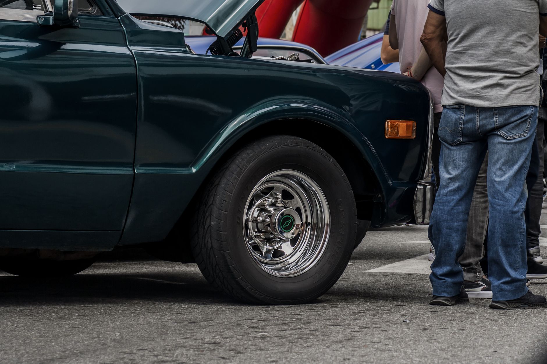 Vintage car with chrome wheel and open hood, showcased in Mérida, Venezuela.